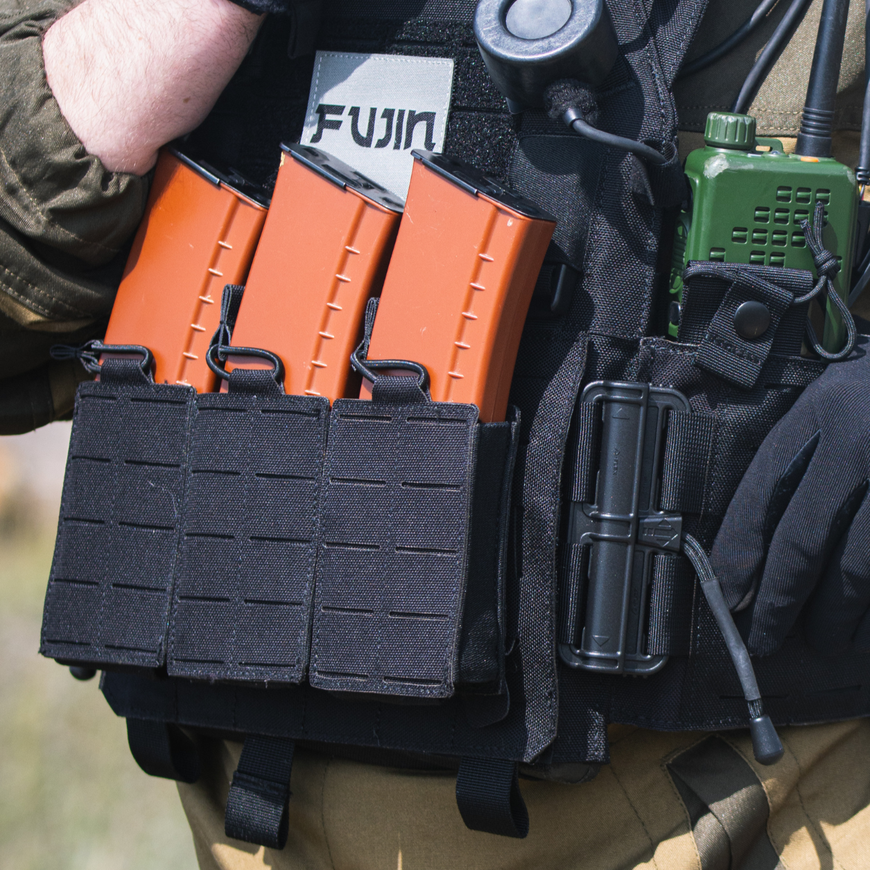 Person wearing tactical gear with a Fujin camera mount in an outdoor setting