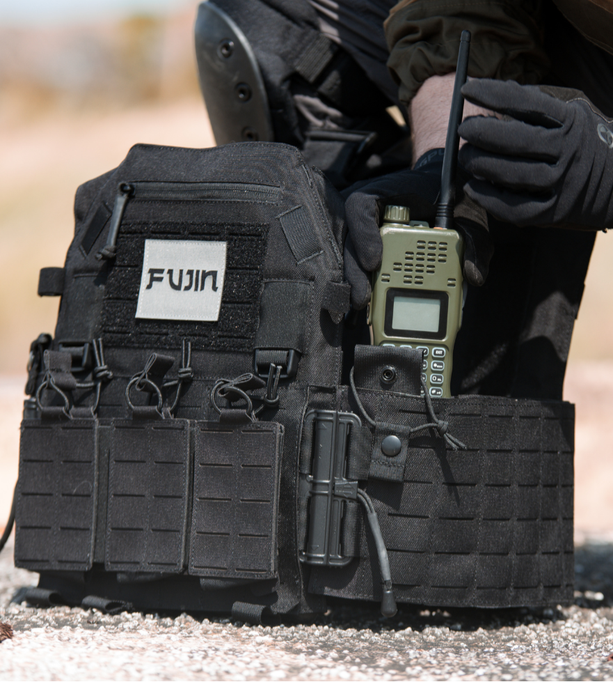Person wearing tactical gear with a radio and Fujin logo on a blurred background